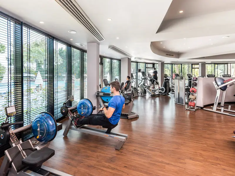Trainierende an Fitnessgeräten vor der Fensterfront des Rixos Downtown Antalya