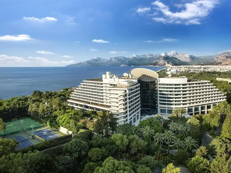 Rixos Downtown Antalya zwischen grünen Parkflächen und Küste mit Bergen im Hintergrund