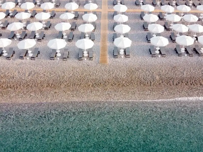 Reihen weißer Sonnenschirme und Liegen am Strand des Rixos Downtown Antalya