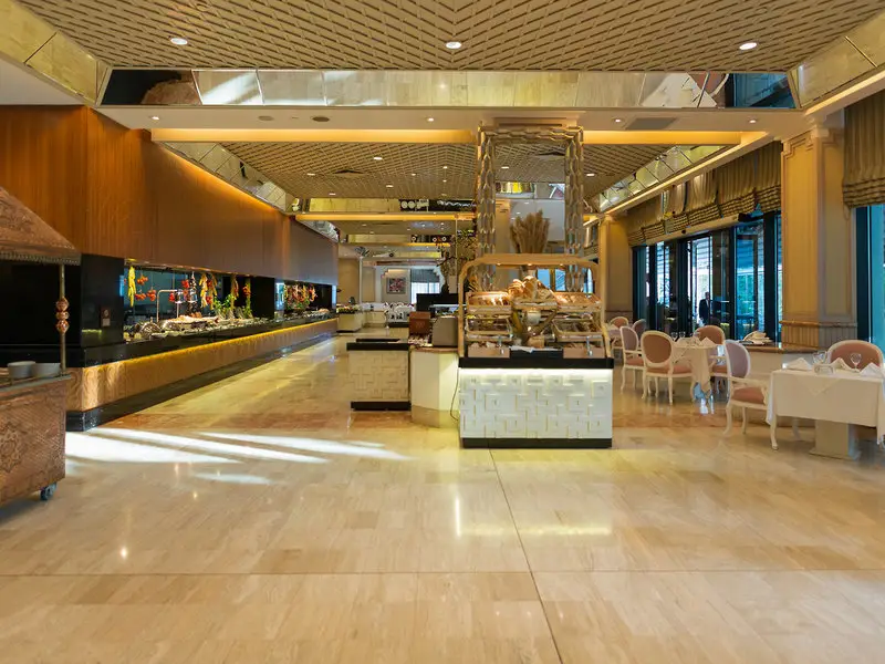 Buffetrestaurant im Rixos Downtown Antalya mit goldfarbener Decke, Buffetstationen und gedeckten Tischen